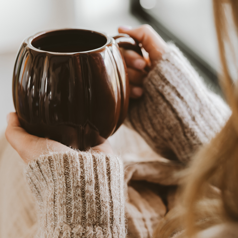 Person holding a brown mug with a blurred background