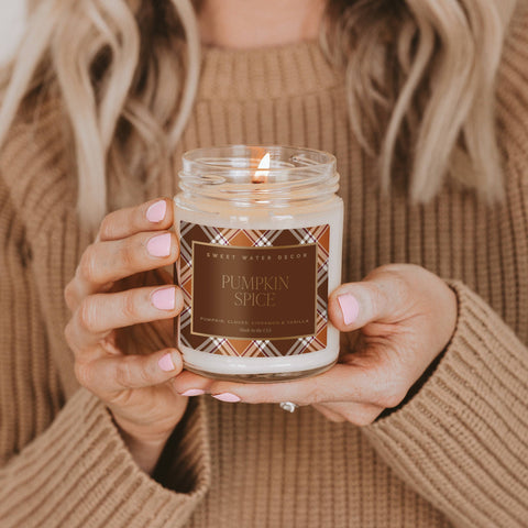 Person holding a 'Pumpkin Spice' candle with a plaid label