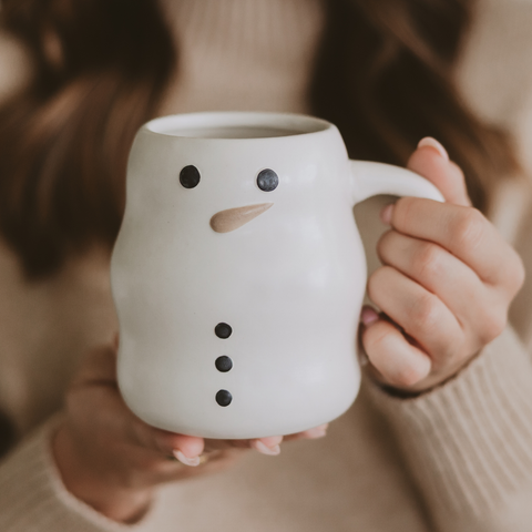 Person holding a snowman-shaped ceramic mug