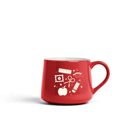 A red ceramic coffee mug with a white graphic print of school and office supplies, including a ruler, pencil, scissors, and apple, on a clean white background.