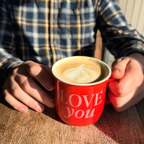 Red mug with 'LOVE You' text held by person in flannel shirt