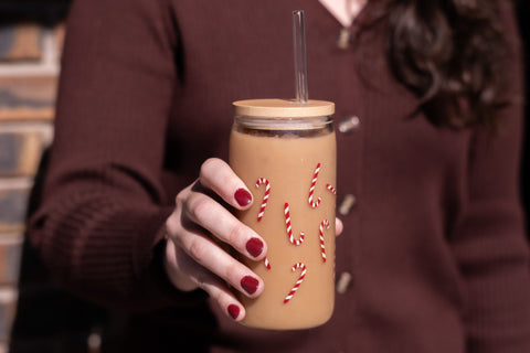 Woman's hand holding a glass tumbler containg and iced coffee drink