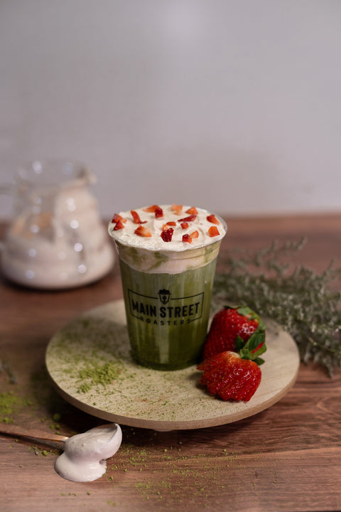 Strawberry Bloom Matcha in Main Street Roasters cup on wood surface