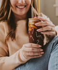 Woman holding a festive-themed cup with a straw, smiling.