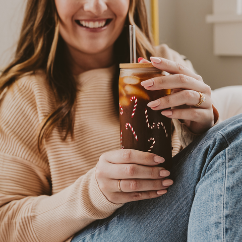 Woman holding a festive-themed cup with a straw, smiling.
