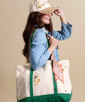 Woman wearing a cap and holding a tote bag with decorative elements on a beige background