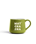 A green ceramic coffee mug with the words 'MAT CHA CHA' printed in white on the front, set against a plain white background.