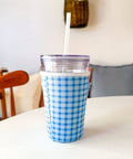 Blue and white checkered cup with a straw on a white surface