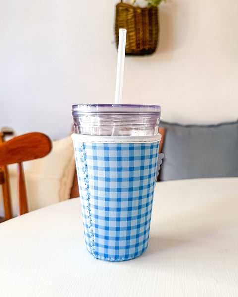 Blue and white checkered cup with a straw on a white surface