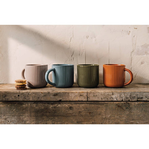 Four ceramic mugs in different colors on a wooden surface with a neutral background