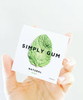 Hand holding a package of Simply Gum with a mint leaf on a white background