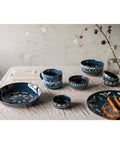 Set of blue ceramic dishes with floral patterns on a light fabric surface.