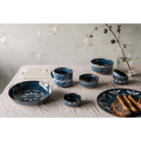 Set of blue ceramic dishes with floral patterns on a light fabric surface.