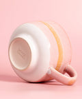 Pink ceramic mug with a textured handle on a pink background, featuring the Nova Ceramics logo.