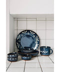 Set of blue ceramic dinnerware with white patterns on a tiled kitchen floor.