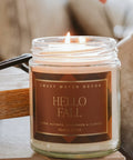 Candle in a jar with 'Hello Fall' label on a wooden surface