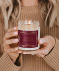 Person holding a 'Autumn Orchard' candle with a warm background