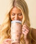 Woman holding a tan floral-patterned mug with a beige background