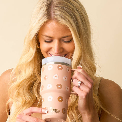 Woman holding a tan floral-patterned mug with a beige background