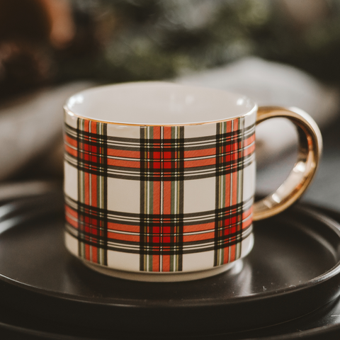 Plaid-patterned mug on a black saucer with a blurred background