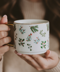 Person holding a mug with floral patterns