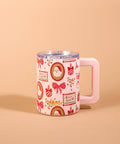A pink handled mug decorated with a Christmas-themed pattern of red bows, gold wreaths, and holiday stamps, featuring a light pink handle and a clear lid, set against a solid beige background.