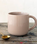 Pink ceramic mug with handle on a wooden surface