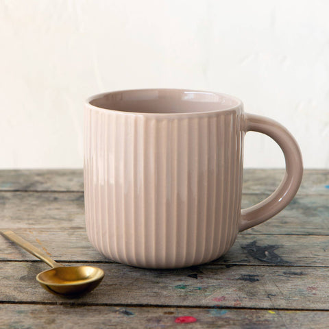 Pink ceramic mug with handle on a wooden surface