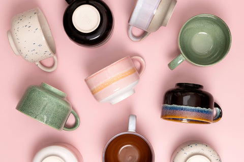 Collection of colorful mugs on a pink background