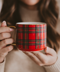 Red plaid mug held by a person wearing a beige sweater.