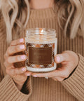 Person holding a 'Pumpkin Spice' candle with a plaid label