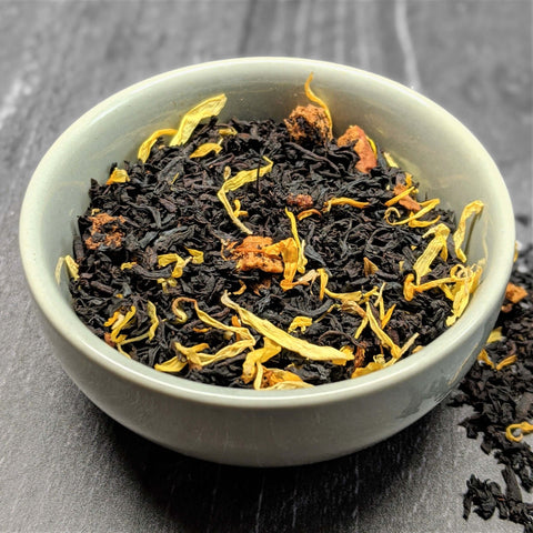 Tea leaves with floral elements in a white bowl on a dark surface - Little Prayer Tea Company 