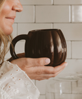 Person holding a brown mug in a kitchen setting