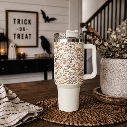 White tumbler with Halloween design on a wooden table, with decorative elements in the background.