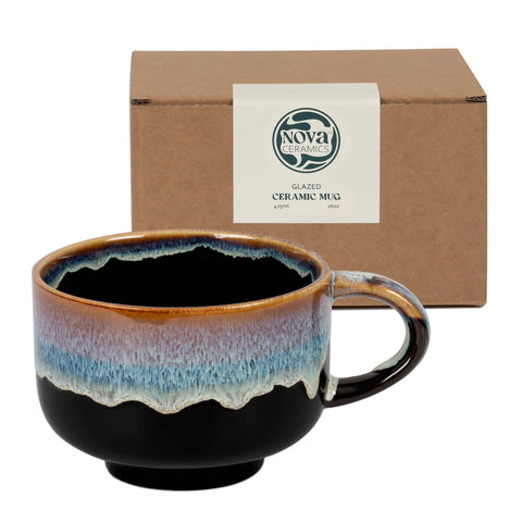 Nova Ceramics ceramic mug with multicolored glaze in front of a brown box.