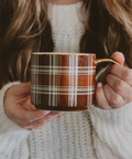 Person holding a plaid mug with a soft focus background