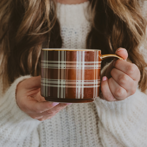 Person holding a plaid mug with a soft focus background
