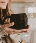 Person holding a black mug in a kitchen setting
