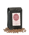 Black coffee bag with a pink label and scattered coffee beans on a white background