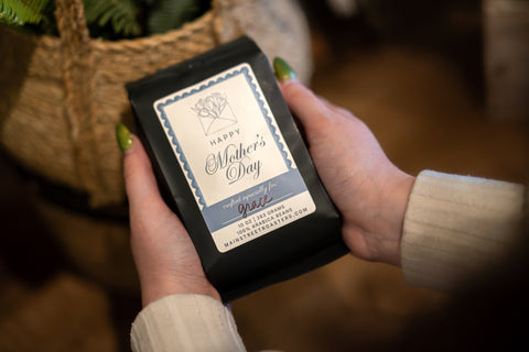 Hand holding a small black box with a 'Happy Mother's Day' label.