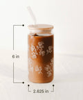 Brown tumbler with floral patterns and straw on a white background with dimensions