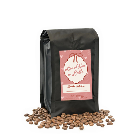Black coffee bag with 'Love You a Latte' label and scattered coffee beans on a white background