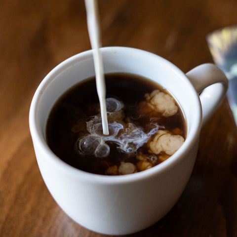 Pouring Cream Into Mug of Coffee
