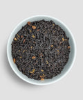 Dry black tea leaves in a white bowl on a light gray background - Little Prayer Tea Company 