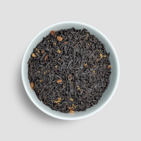 Dry black tea leaves in a white bowl on a light gray background - Little Prayer Tea Company 