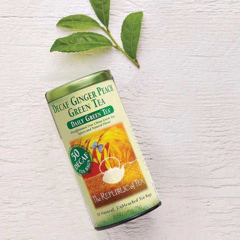 Decaf Ginger Peach Green Tea canister with green leaves on a white background