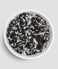 White bowl filled with a mix of black and white tea leaves on a light gray background - Little Prayer Tea Company 