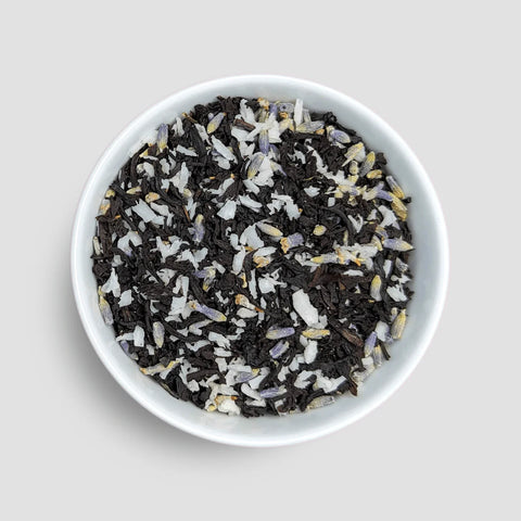 White bowl filled with a mix of black and white tea leaves on a light gray background - Little Prayer Tea Company 