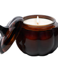 Candle in a brown glass jar with a lid on a white background