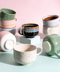 Collection of colorful ceramic mugs on a pastel background